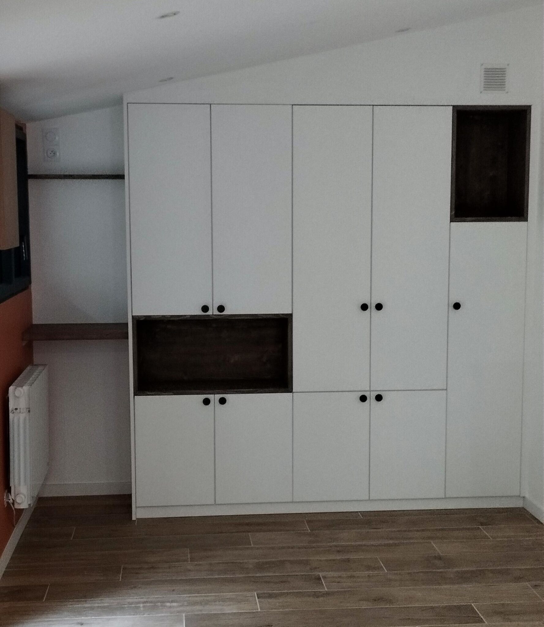 Aménagement d’une salle de réunion avec rangements en mélaminé blanc, niches en pin et étagères flottantes.