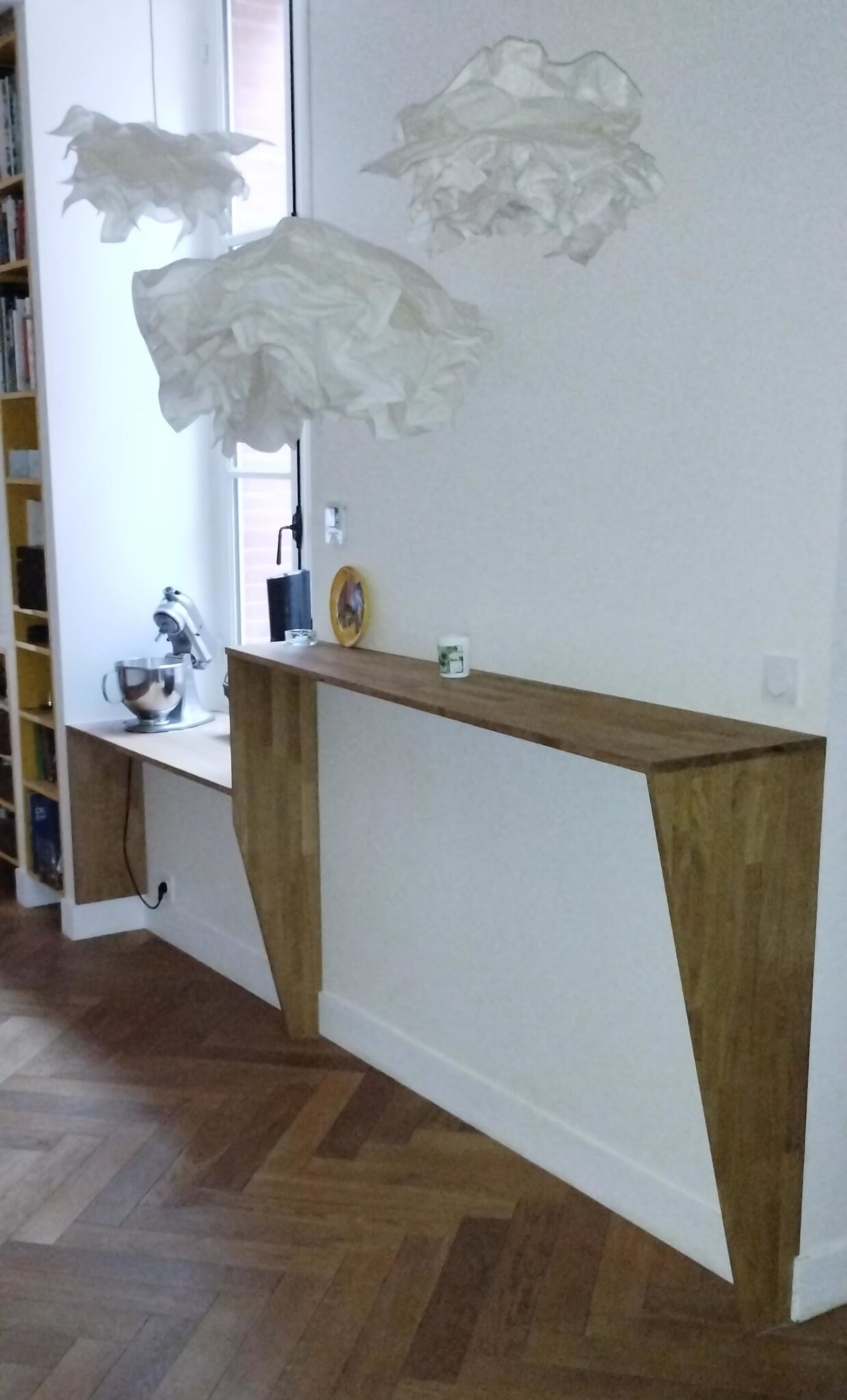 Mange Debout Mange-debout mural en chêne lamellé collé, design épuré avec pieds inclinés, installé au-dessus d’un parquet en chevrons