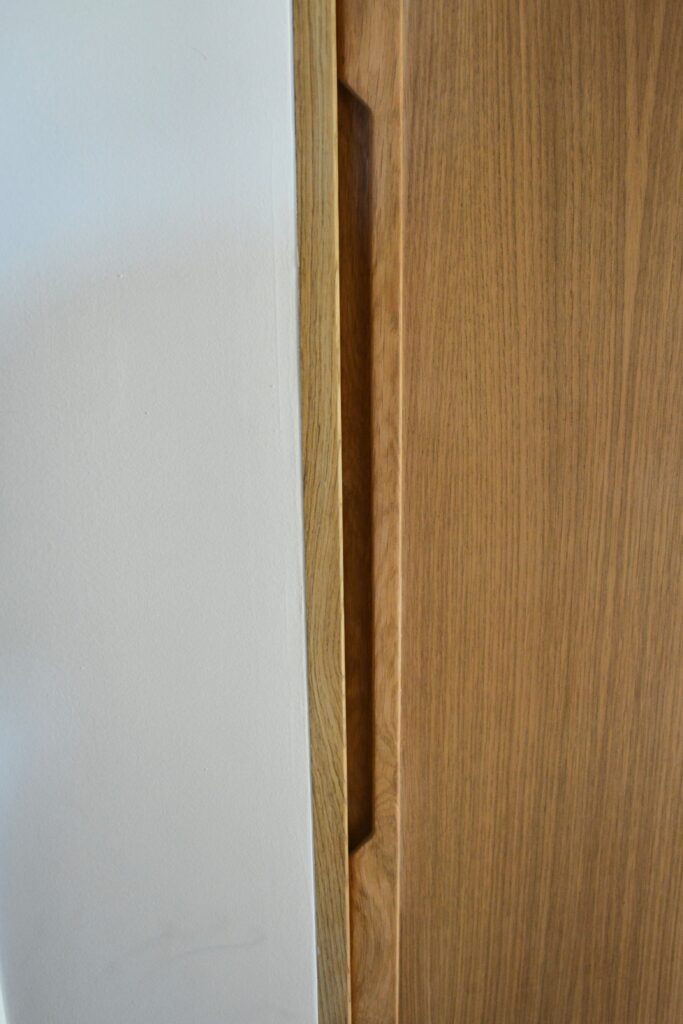Détail de la prise de main usinée dans une porte de placard en chêne massif, réalisation sur mesure